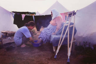 A Kosovar-Albanian young woman washes the feet of her grandmother in a refugee camp during the war in Kosovo, Kukes, Albania